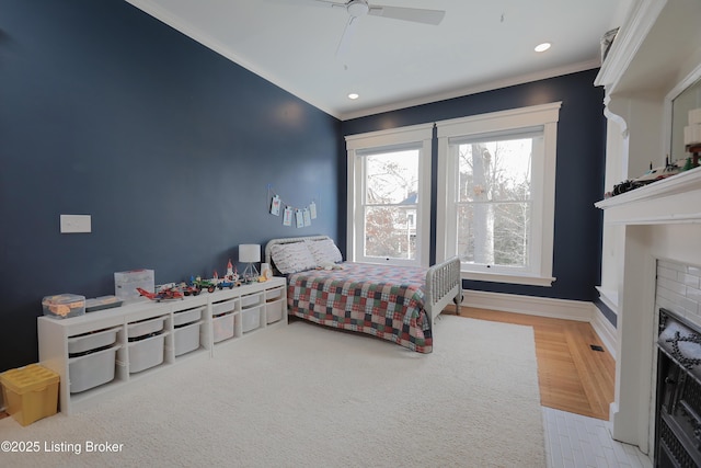 bedroom with baseboards, a fireplace with flush hearth, ceiling fan, crown molding, and recessed lighting