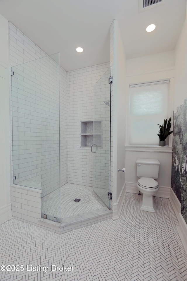 bathroom with a stall shower, tile patterned flooring, baseboards, and toilet