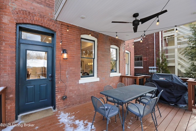 wooden deck with outdoor dining space, ceiling fan, and grilling area