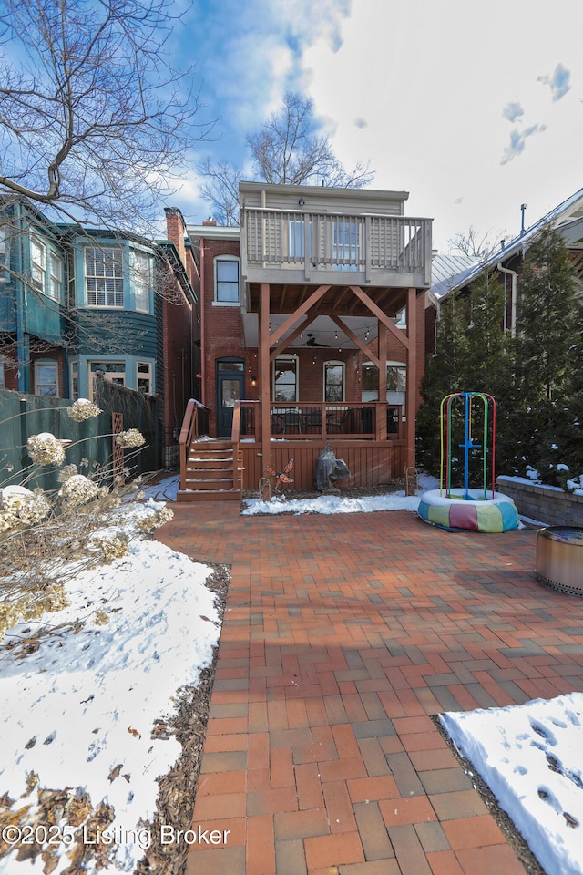 snow covered back of property with a balcony