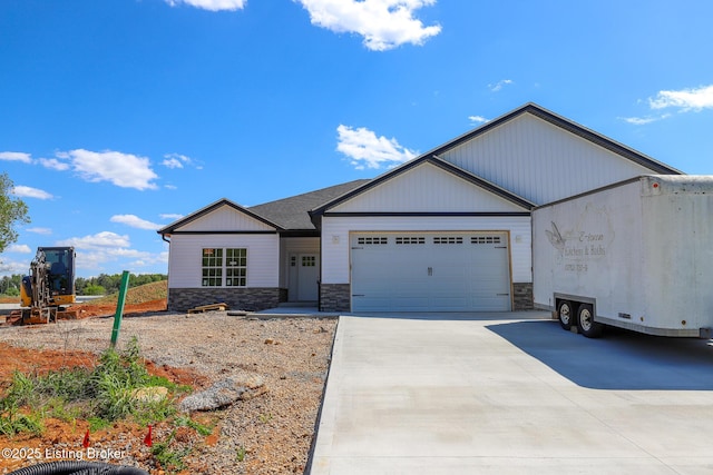 view of front of home featuring a garage, stone siding, and driveway