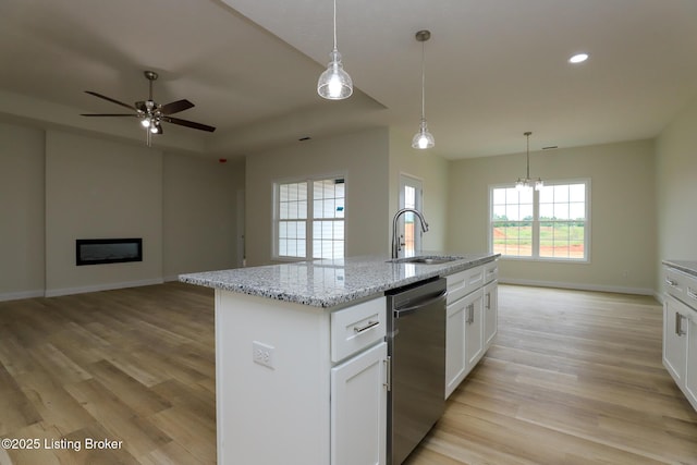 kitchen with open floor plan, white cabinets, a sink, and stainless steel dishwasher