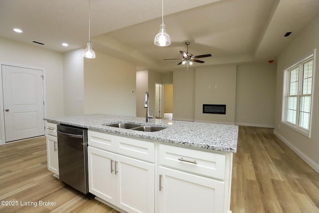 kitchen featuring open floor plan, white cabinetry, a sink, and stainless steel dishwasher