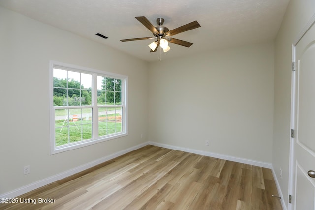 spare room with visible vents, ceiling fan, light wood-style flooring, and baseboards