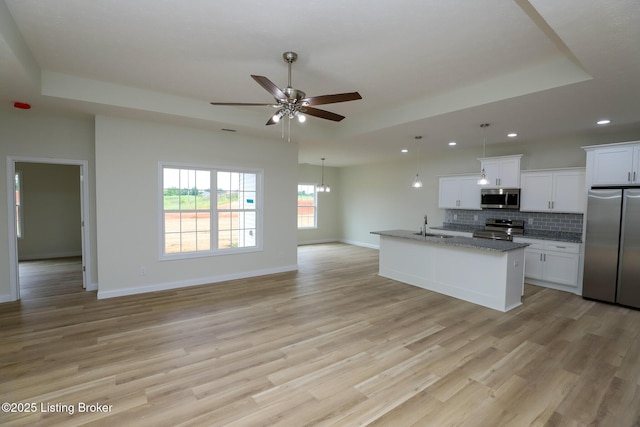 kitchen featuring a center island with sink, appliances with stainless steel finishes, open floor plan, white cabinetry, and a sink