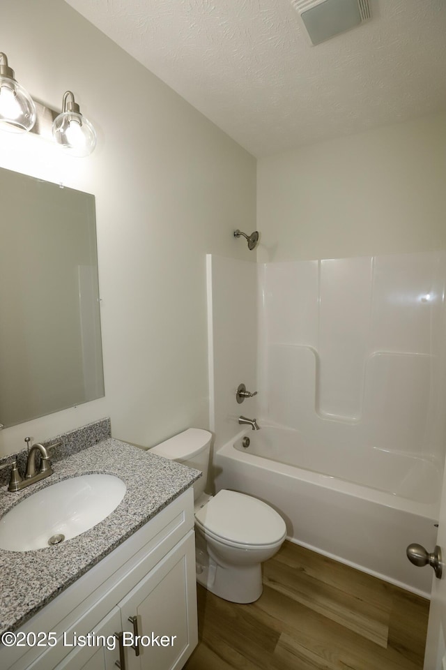 full bath featuring shower / bathtub combination, a textured ceiling, wood finished floors, visible vents, and vanity