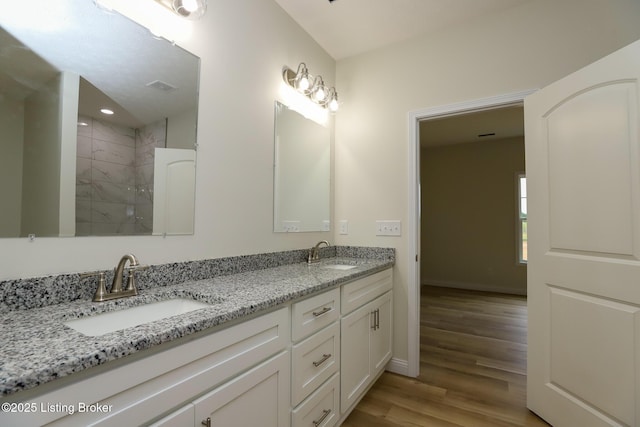 full bath featuring double vanity, visible vents, a sink, and wood finished floors