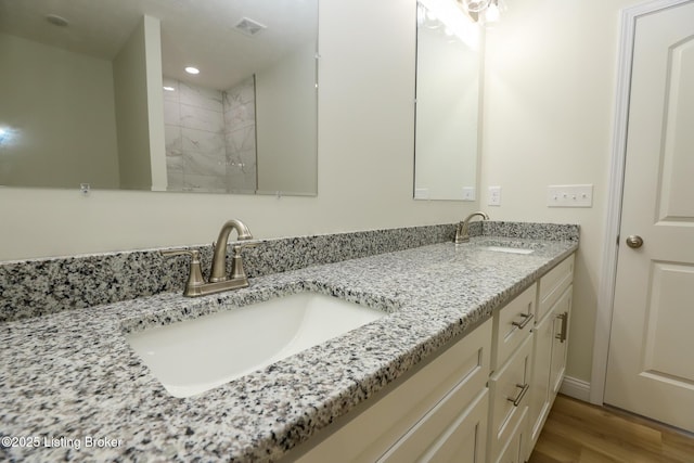 bathroom with double vanity, wood finished floors, a sink, and visible vents