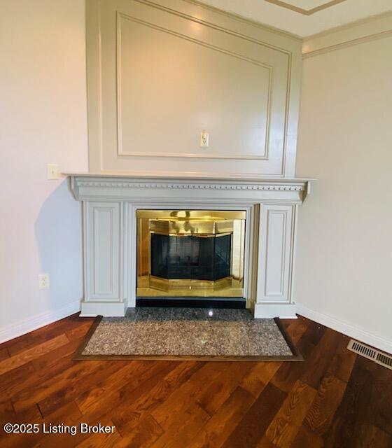 room details with a fireplace with flush hearth, visible vents, baseboards, and wood finished floors