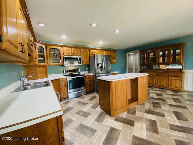 kitchen featuring a sink, stainless steel appliances, light countertops, and glass insert cabinets