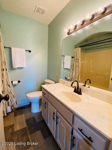 bathroom with curtained shower, visible vents, toilet, vanity, and wood finished floors