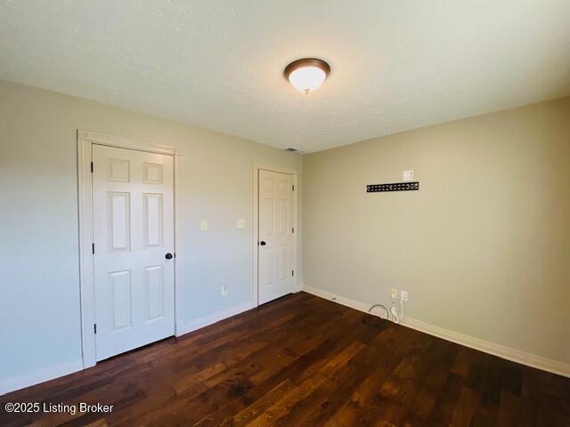 unfurnished bedroom featuring baseboards and dark wood finished floors