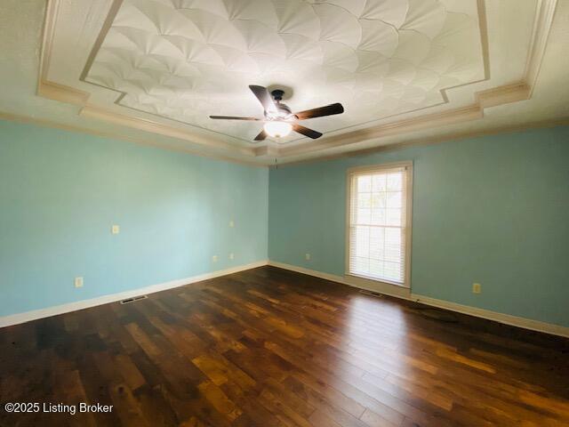 spare room featuring baseboards, dark wood-style flooring, a raised ceiling, and crown molding