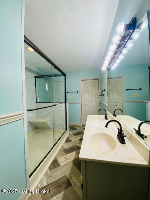 bathroom with double vanity, a shower stall, a closet, and a sink