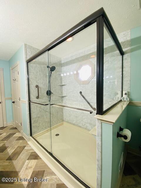 bathroom featuring a shower stall and a textured ceiling