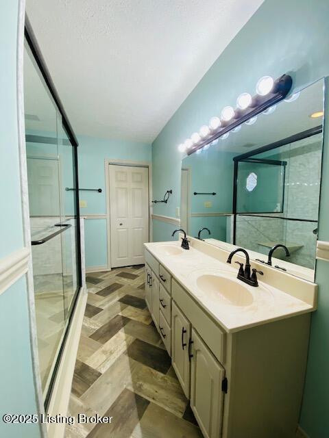 bathroom featuring vaulted ceiling, double vanity, a stall shower, and a sink