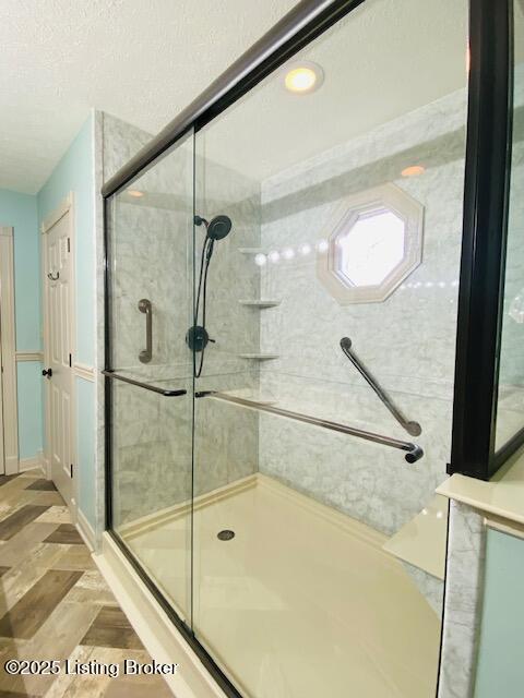 full bathroom featuring a shower stall and a textured ceiling