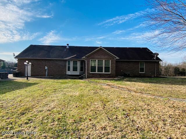 back of house featuring brick siding and a lawn