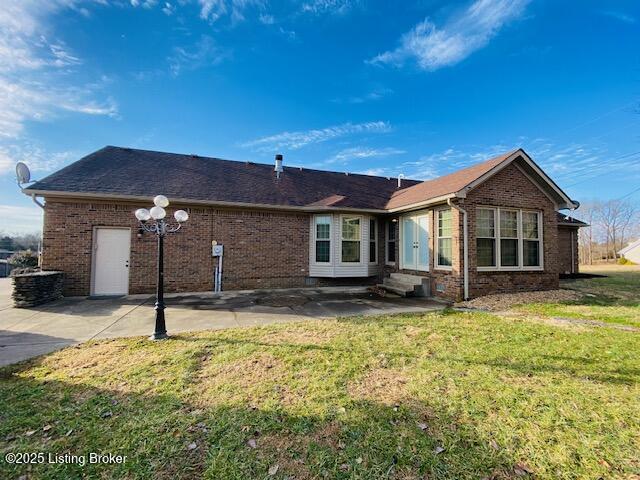 rear view of property with entry steps, a yard, and brick siding