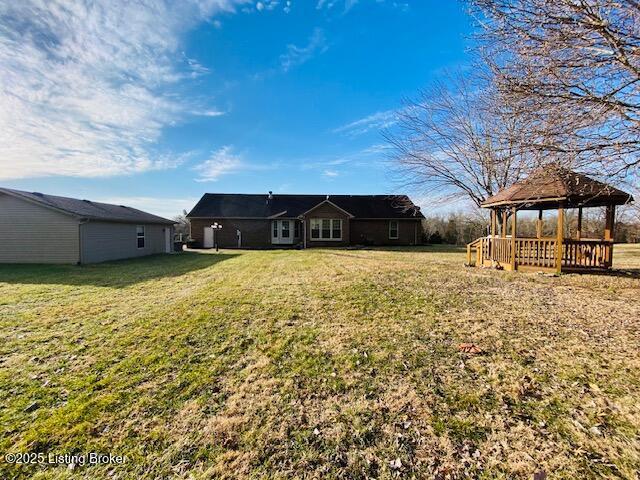 back of property with a yard and a gazebo