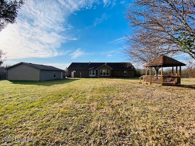 back of property featuring a yard and a gazebo