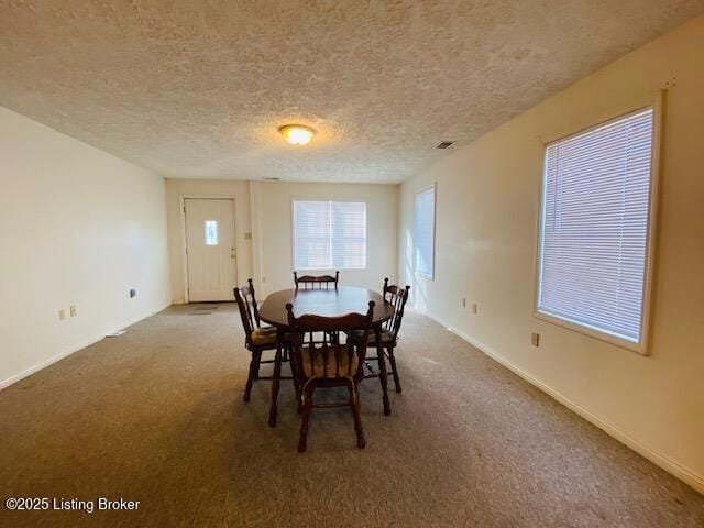 carpeted dining space with a textured ceiling and baseboards