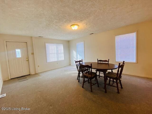 dining area with a textured ceiling and carpet