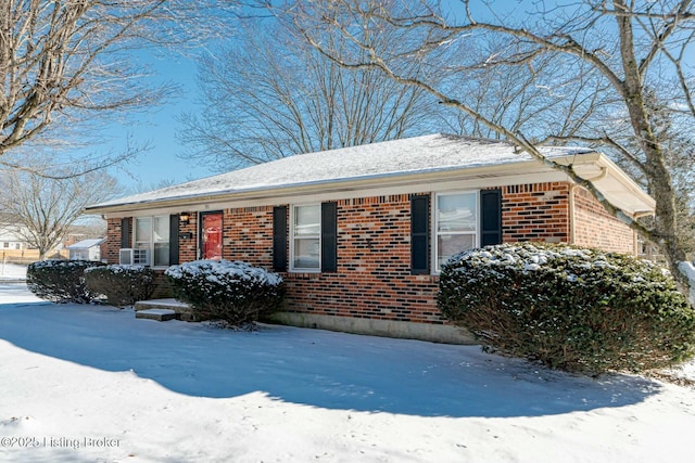 snow covered property featuring brick siding