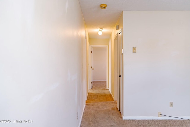 hall featuring light carpet and baseboards