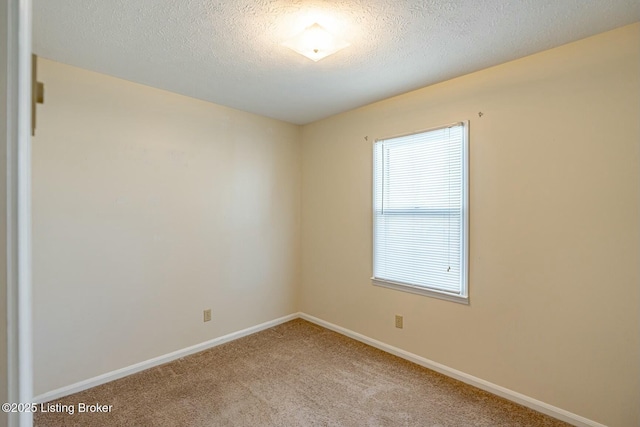 carpeted spare room featuring baseboards and a textured ceiling