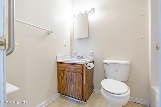 bathroom with toilet, vanity, and baseboards