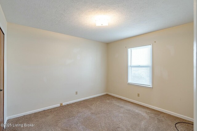 carpeted spare room with a textured ceiling and baseboards