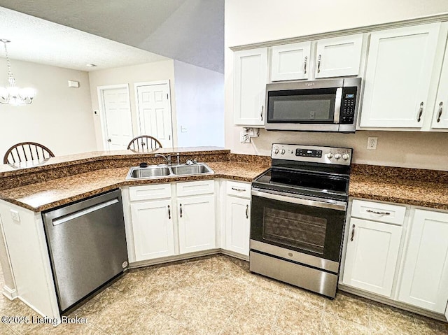 kitchen featuring hanging light fixtures, dark countertops, appliances with stainless steel finishes, and a sink