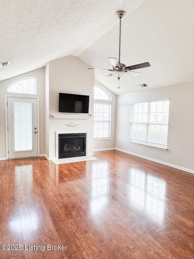 unfurnished living room with light wood-style floors, a fireplace with flush hearth, visible vents, and a textured ceiling