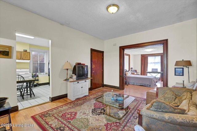 living room with light wood finished floors, baseboards, and a textured ceiling