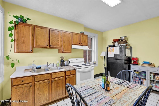 kitchen with white electric range oven, freestanding refrigerator, light countertops, under cabinet range hood, and a sink