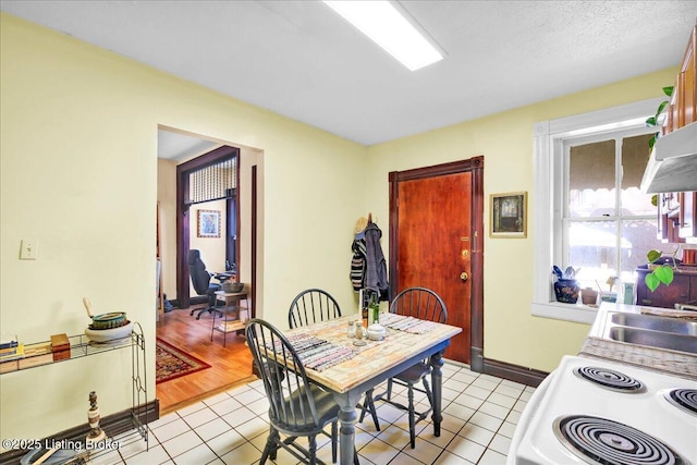 dining area with light tile patterned floors, a textured ceiling, and baseboards