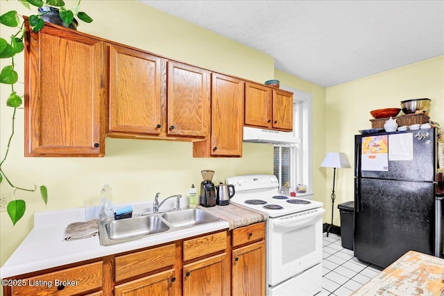 kitchen with electric stove, light countertops, freestanding refrigerator, a sink, and under cabinet range hood