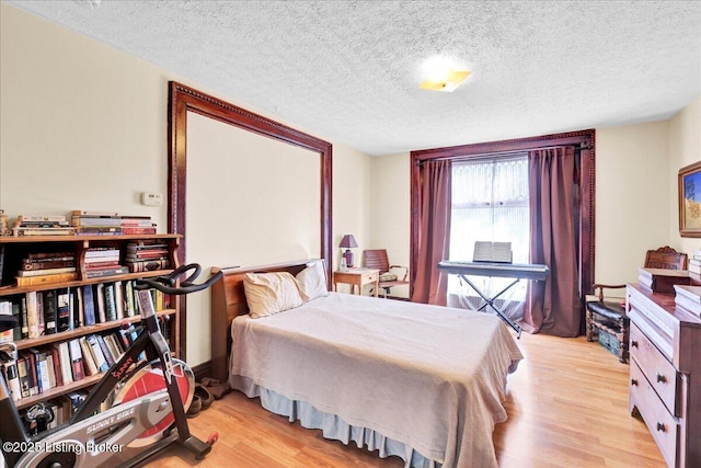 bedroom with light wood-type flooring and a textured ceiling