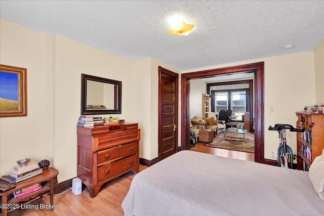 bedroom featuring baseboards, a textured ceiling, and light wood finished floors