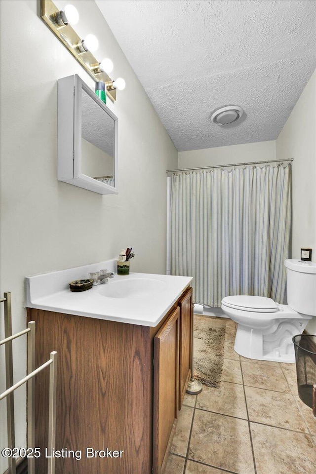 bathroom with a textured ceiling, tile patterned flooring, vanity, and toilet