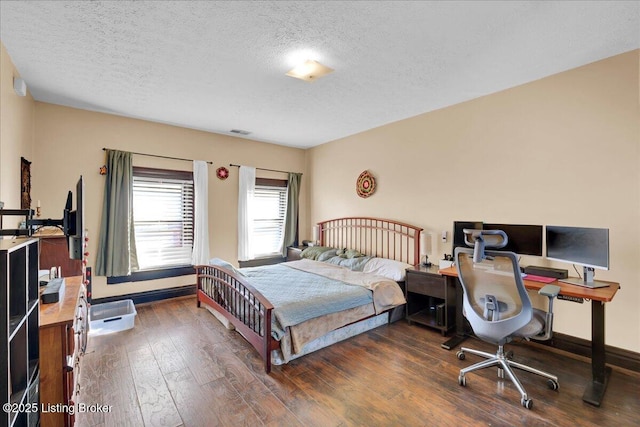 bedroom with dark wood-style floors, baseboards, visible vents, and a textured ceiling