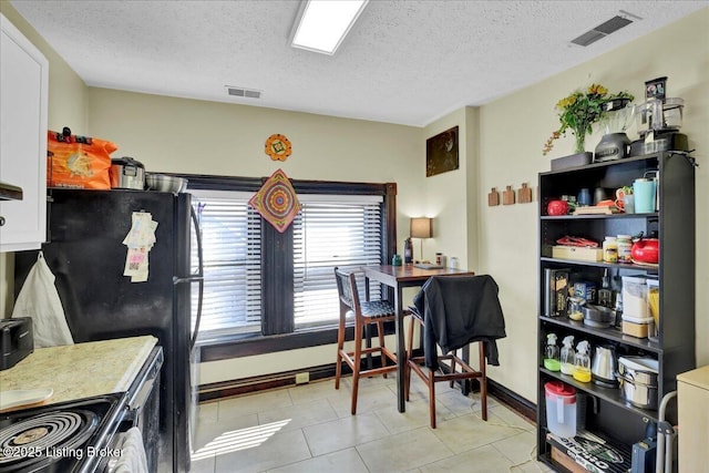 kitchen featuring black range with electric cooktop, white cabinets, visible vents, and a textured ceiling