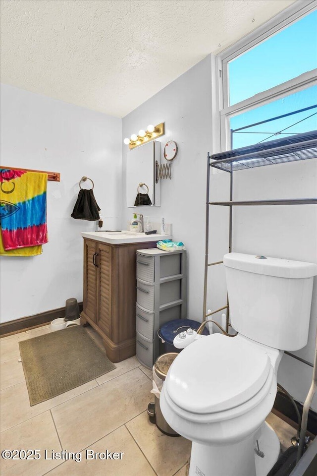 half bath featuring a textured ceiling, vanity, toilet, and tile patterned floors