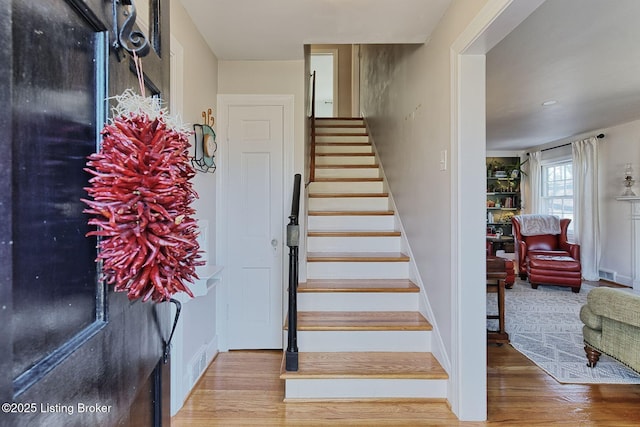 staircase featuring baseboards and wood finished floors