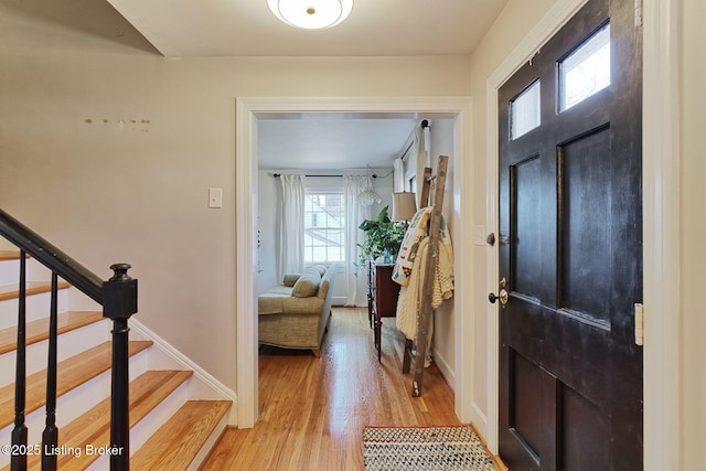 foyer featuring light wood-style floors, baseboards, and stairway