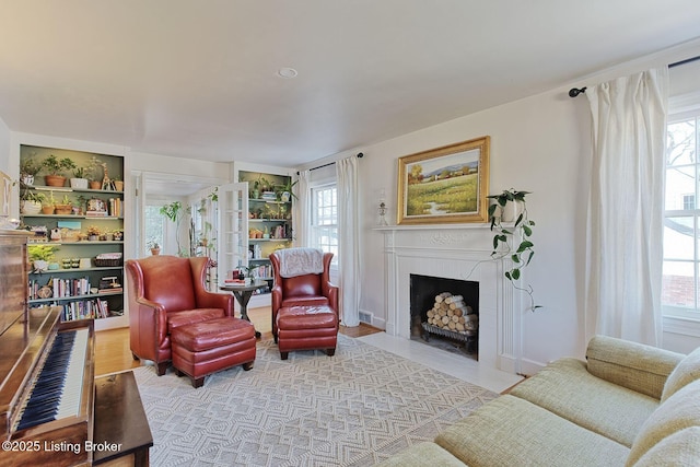 living room with a healthy amount of sunlight, a fireplace with flush hearth, and light wood-style flooring