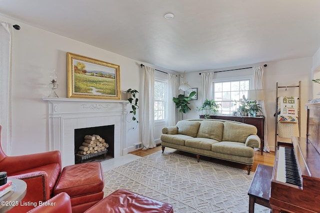 living room with a fireplace with flush hearth, visible vents, and light wood-style flooring