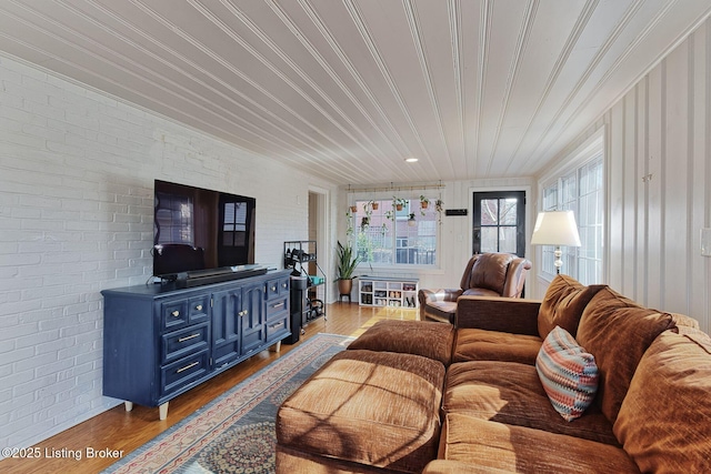 living area featuring brick wall and wood finished floors