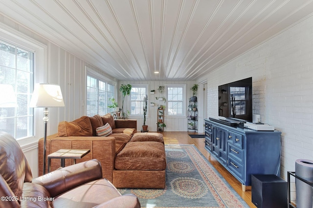 living area featuring light wood-type flooring and brick wall